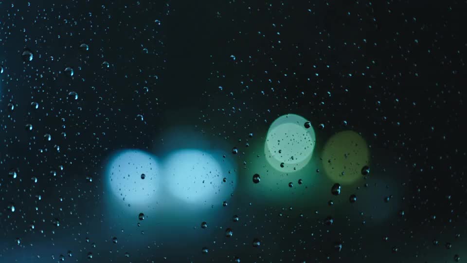 Rain races down a dark window, the city far out of focus